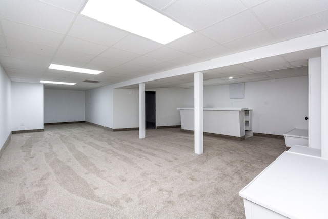 basement featuring light carpet and a paneled ceiling