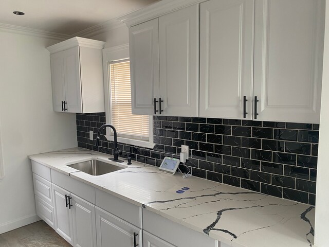 kitchen featuring white cabinetry, light stone countertops, and sink