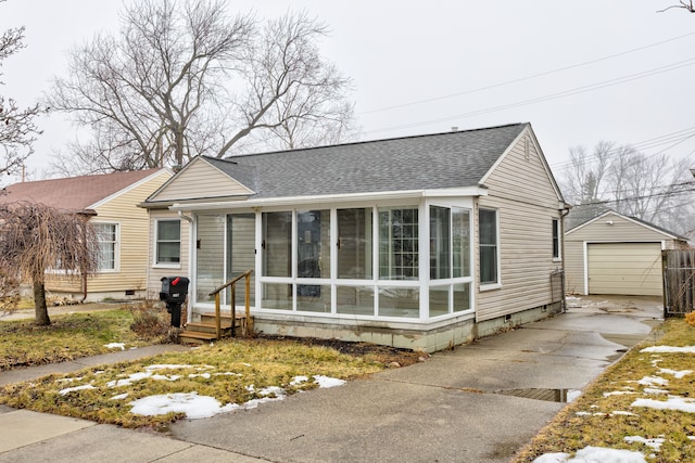 view of front of home featuring an outbuilding, a garage, and a sunroom