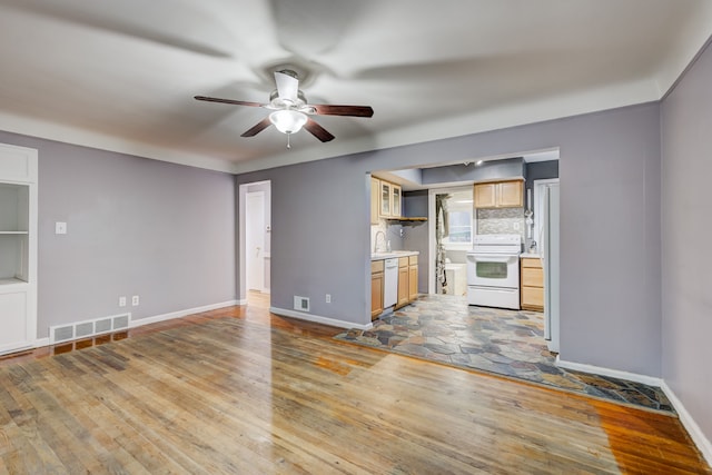 unfurnished living room featuring ceiling fan, sink, and light wood-type flooring