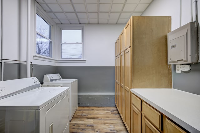 washroom featuring cabinets, electric panel, washer and dryer, and light wood-type flooring