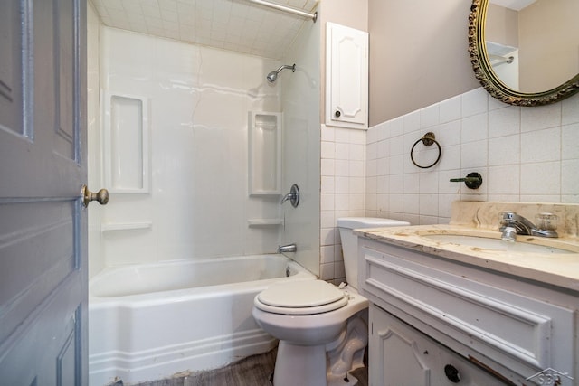 full bathroom with washtub / shower combination, vanity, toilet, and tile walls