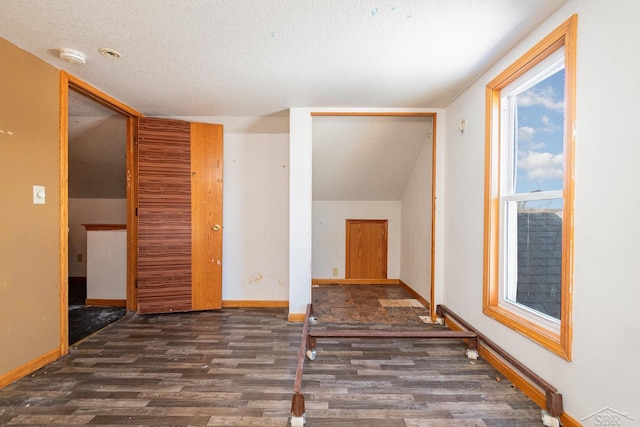 unfurnished room featuring dark wood-type flooring and a textured ceiling