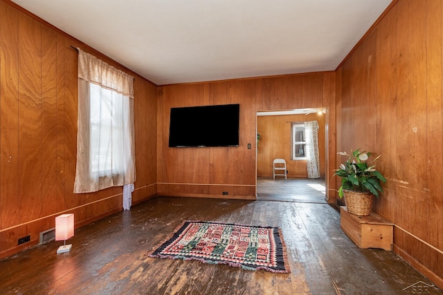 unfurnished living room with wooden walls, dark hardwood / wood-style floors, and a wealth of natural light