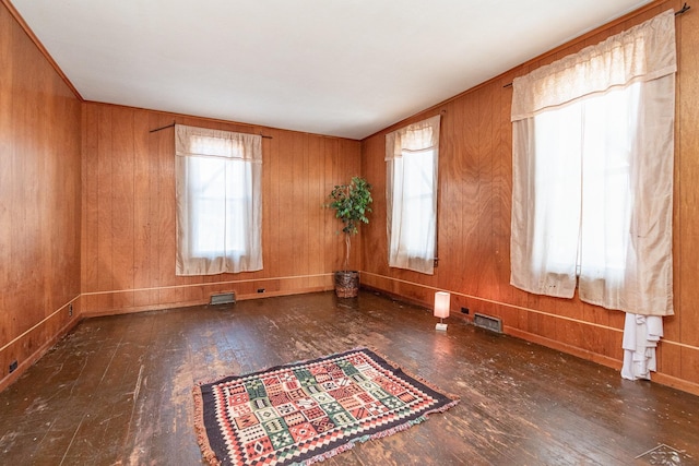 unfurnished room with a healthy amount of sunlight, wooden walls, and dark hardwood / wood-style flooring