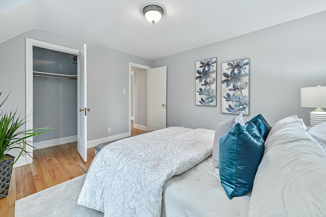 bedroom with lofted ceiling, wood-type flooring, and a closet