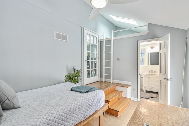 bedroom featuring ceiling fan, connected bathroom, vaulted ceiling with skylight, and sink