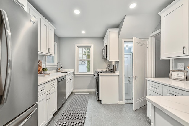 kitchen featuring stainless steel appliances, light stone countertops, sink, and white cabinets