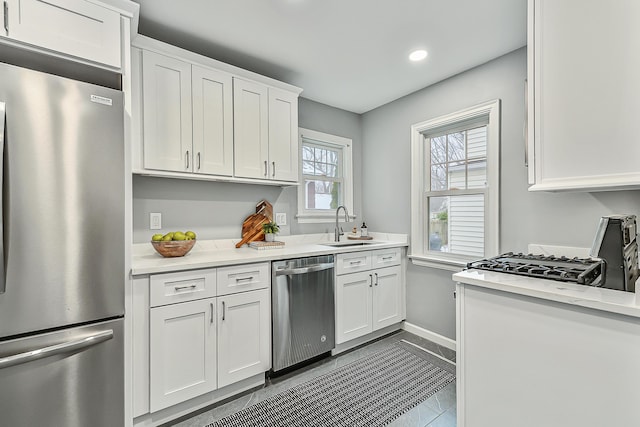 kitchen with stainless steel appliances, white cabinetry, sink, and light tile patterned flooring