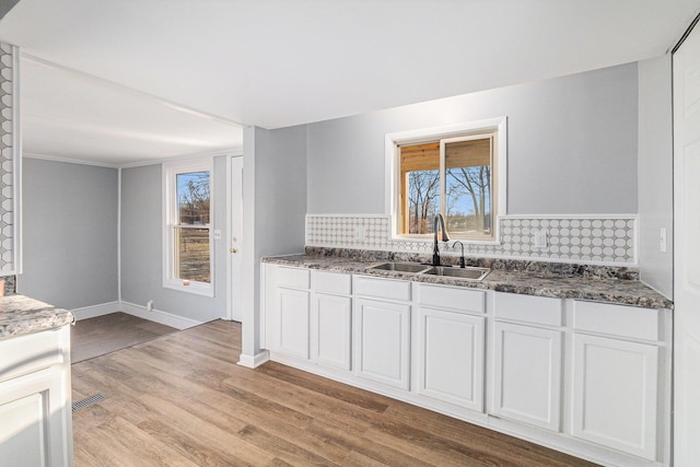 kitchen featuring plenty of natural light, sink, light hardwood / wood-style flooring, and white cabinets