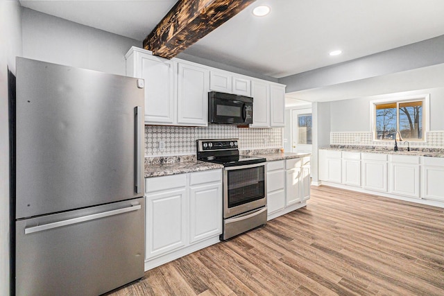 kitchen with appliances with stainless steel finishes, backsplash, light stone counters, light hardwood / wood-style floors, and white cabinets