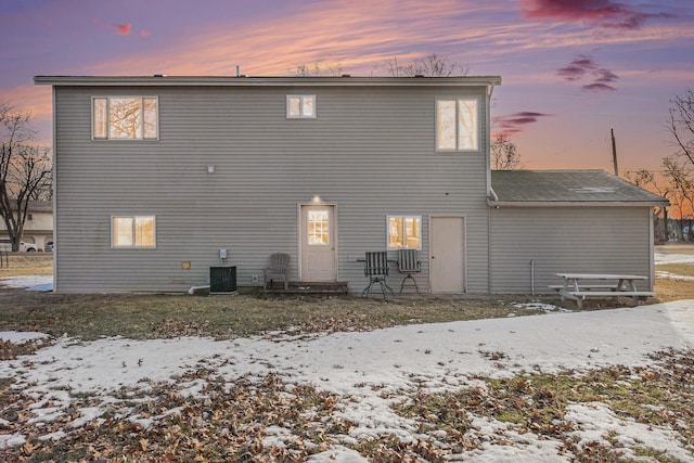 snow covered rear of property featuring central air condition unit