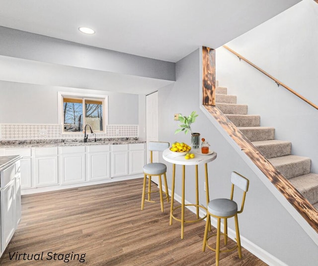 kitchen featuring sink, white cabinets, backsplash, hardwood / wood-style flooring, and light stone countertops