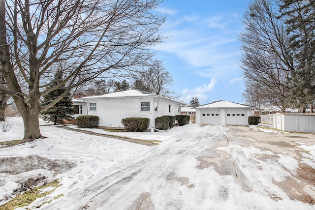 snow covered property featuring a garage and an outdoor structure