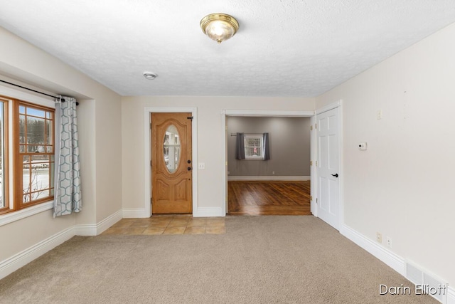 foyer entrance with light colored carpet and a textured ceiling