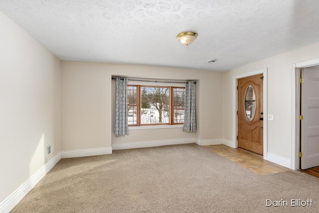 foyer with light colored carpet and a textured ceiling