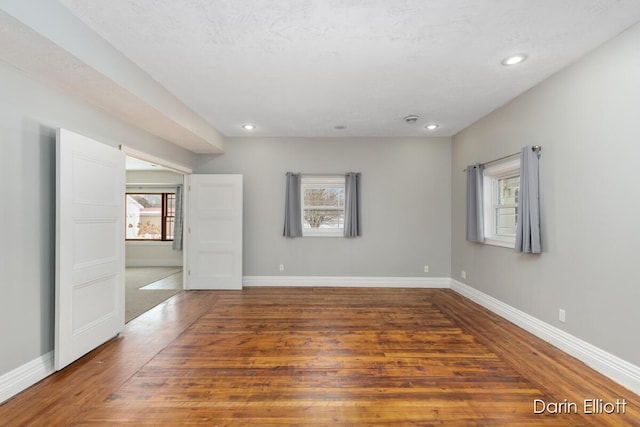 spare room featuring dark hardwood / wood-style flooring, a textured ceiling, and a healthy amount of sunlight