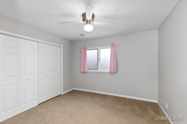 unfurnished bedroom with ceiling fan, carpet floors, a closet, and a textured ceiling