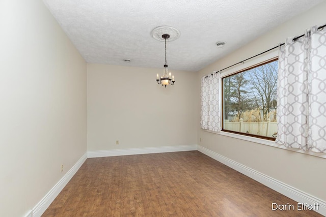 unfurnished room with hardwood / wood-style flooring, a textured ceiling, and a chandelier