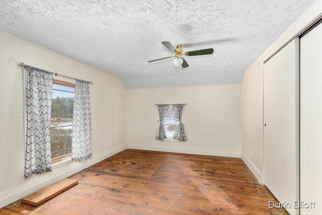 spare room with vaulted ceiling, dark hardwood / wood-style floors, a textured ceiling, and ceiling fan