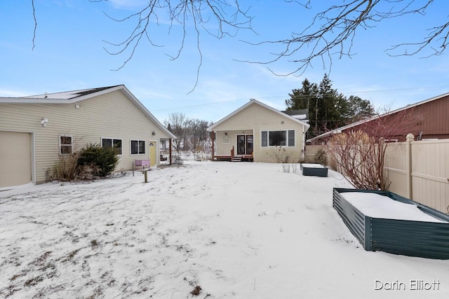 snow covered back of property featuring a garage