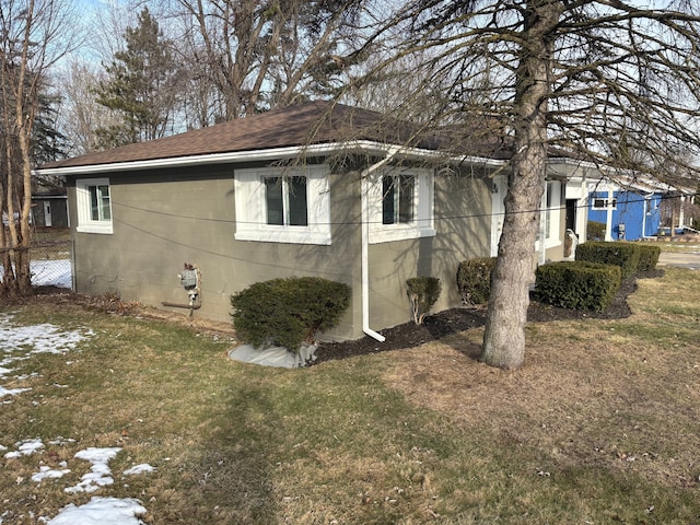 view of property exterior featuring fence, a lawn, concrete block siding, and a shingled roof