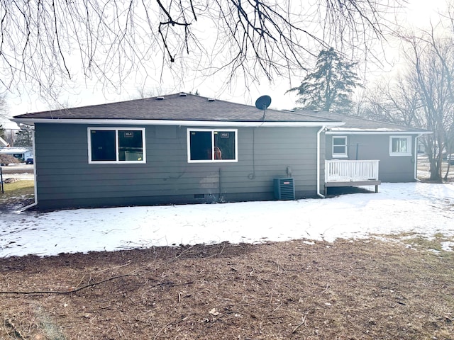 snow covered rear of property featuring central AC unit