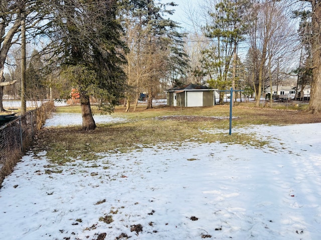 yard covered in snow with a garage, an outdoor structure, and fence