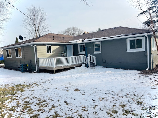 snow covered back of property with cooling unit and a wooden deck