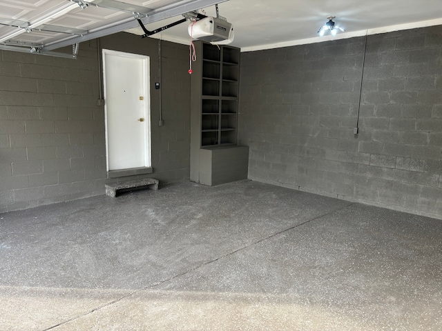 garage featuring concrete block wall and a garage door opener