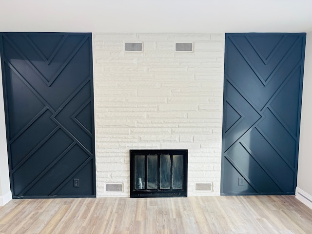 unfurnished living room featuring a stone fireplace and light wood-type flooring