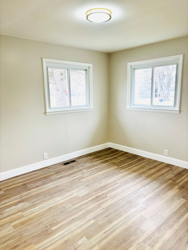 unfurnished room featuring light wood-style floors, baseboards, and a wealth of natural light