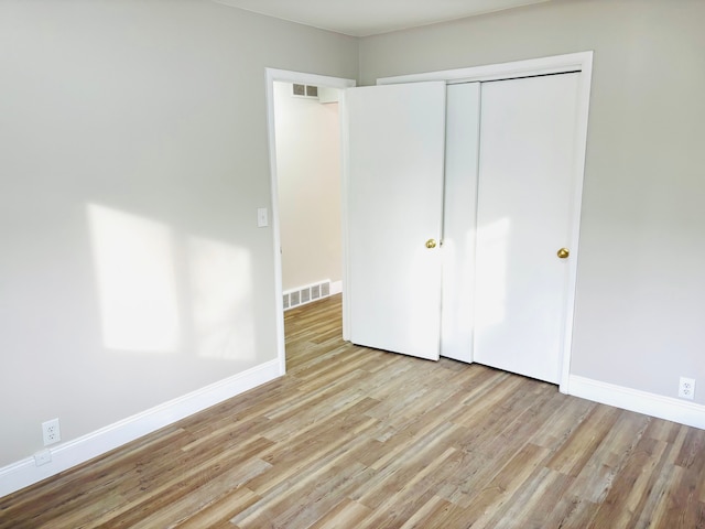 unfurnished bedroom featuring light wood-style floors, visible vents, and baseboards