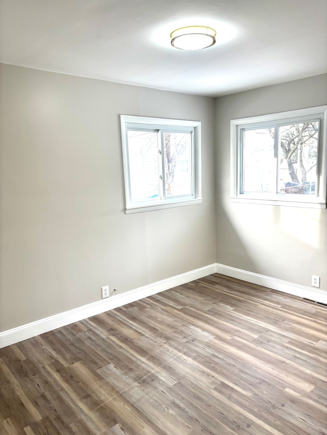 spare room with baseboards and wood finished floors