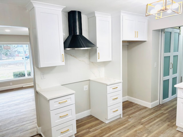 kitchen with wall chimney range hood, light hardwood / wood-style flooring, and white cabinets