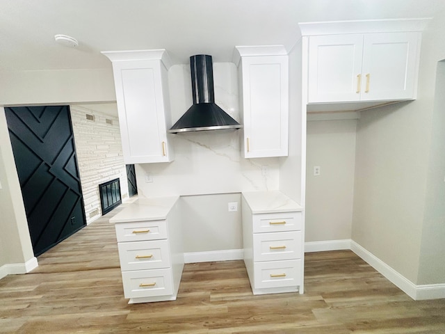 kitchen with white cabinetry, wall chimney range hood, and light hardwood / wood-style floors