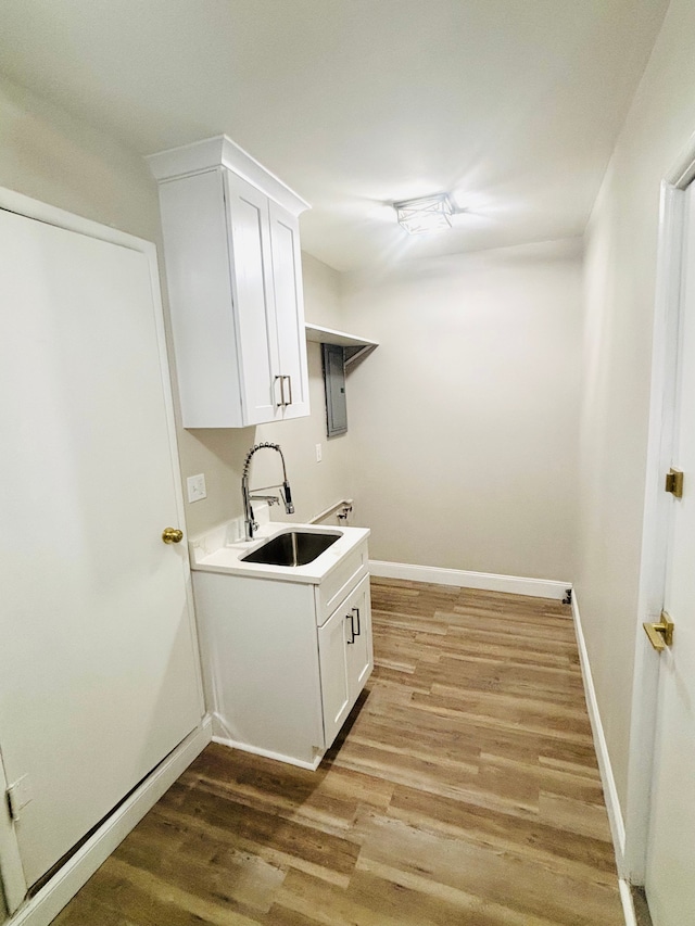 clothes washing area with cabinets, sink, washer hookup, and light hardwood / wood-style flooring