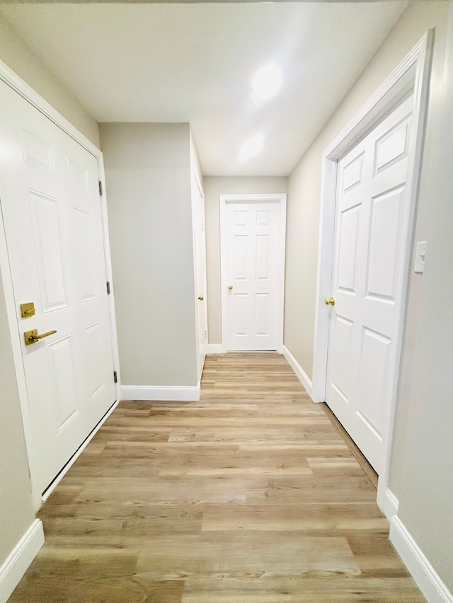 hallway featuring baseboards and light wood-type flooring