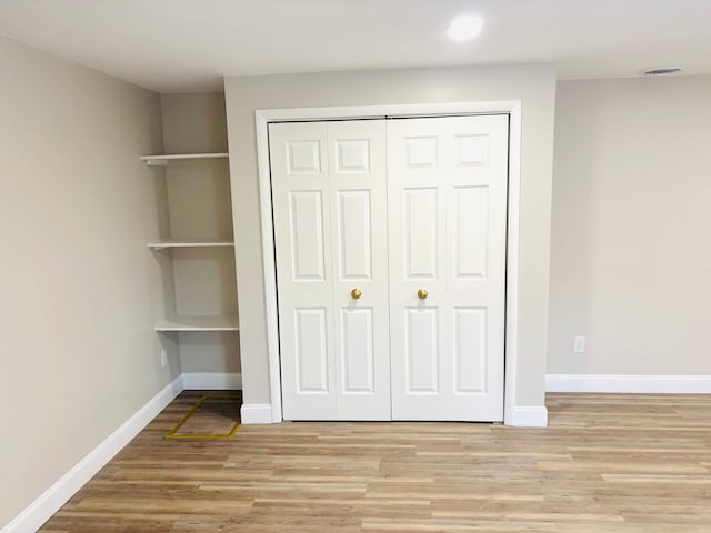 unfurnished bedroom with a closet, baseboards, and light wood-style floors