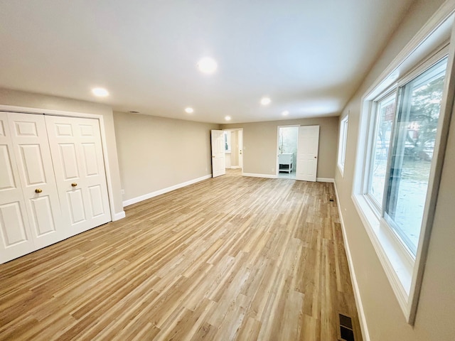 unfurnished living room with recessed lighting, baseboards, and light wood finished floors