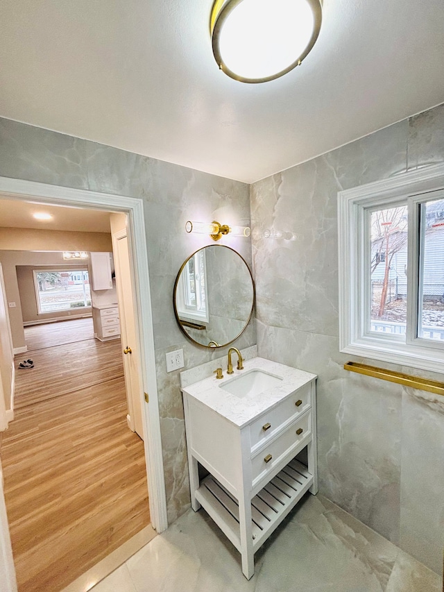 bathroom with vanity, wood-type flooring, tile walls, and a healthy amount of sunlight