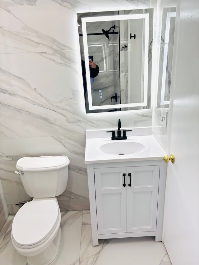 bathroom with toilet, marble finish floor, a shower stall, and vanity