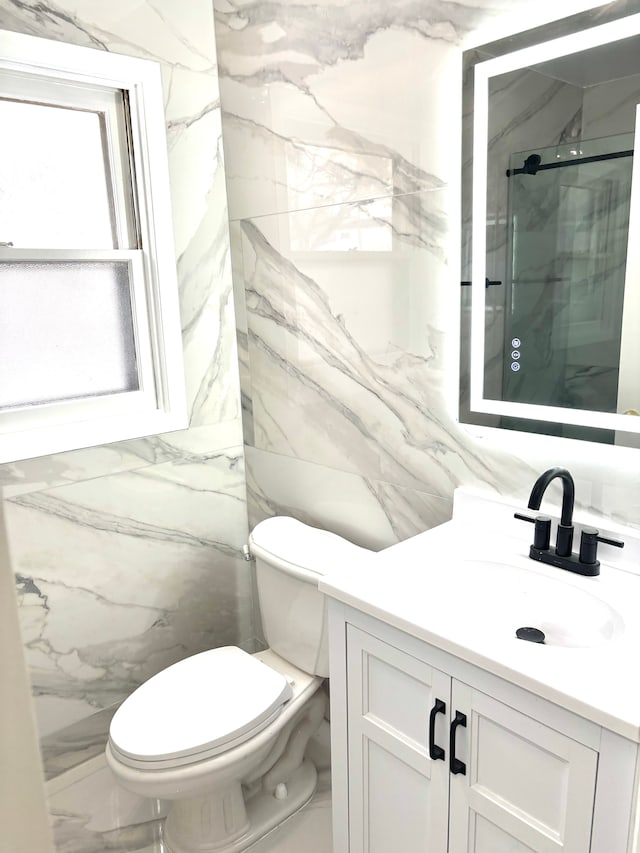 bathroom with a marble finish shower, toilet, and vanity