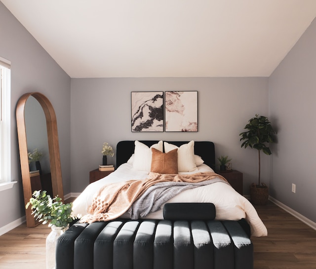 bedroom with lofted ceiling and wood-type flooring