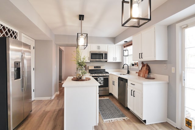 kitchen with sink, white cabinetry, a center island, appliances with stainless steel finishes, and pendant lighting