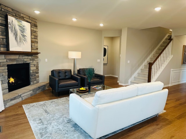 living room with washer / dryer, wood-type flooring, and a stone fireplace