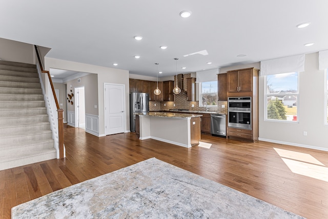 kitchen featuring light stone countertops, stainless steel appliances, a center island, and hanging light fixtures