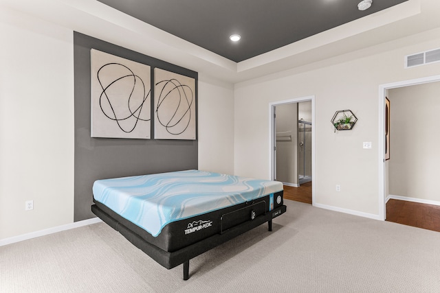 bedroom featuring a raised ceiling, carpet, and a walk in closet