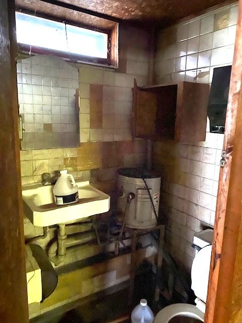 bathroom featuring sink, tile walls, and toilet