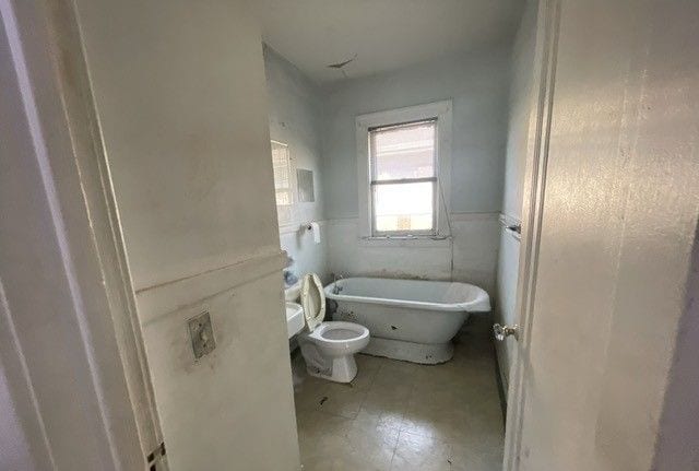 bathroom with tile walls, toilet, and a bathing tub